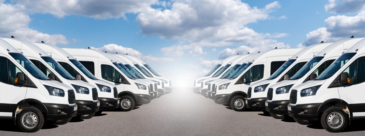 White fleet of Electric vans facing one another with light streaming through the middle 577655589